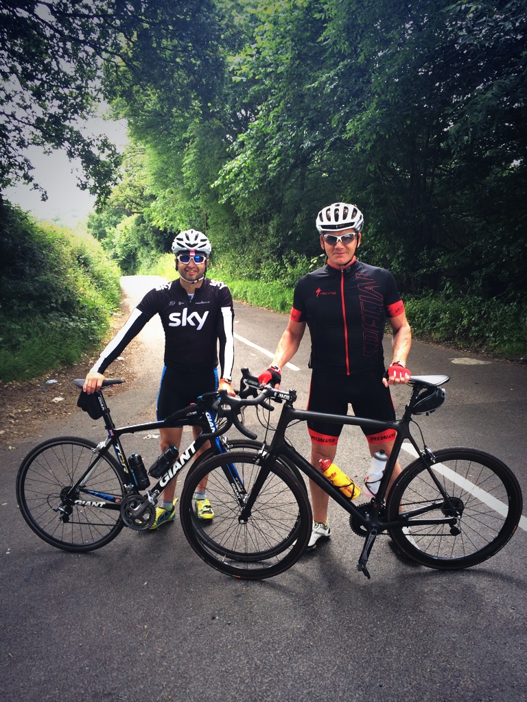 Two cyclists with their bikes on a tree-lined road